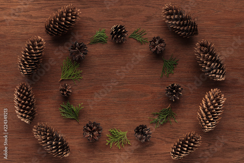 top view of beautiful evergreen coniferous twigs and pine cones on wooden background