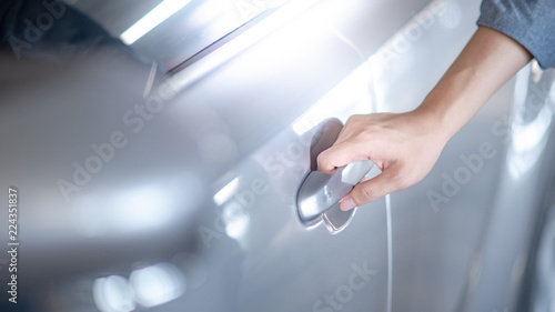 Close up of male hand holding and opening the metallic car door handle. Urban lifestyle with automobile concept