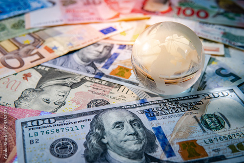 Global business and economy. World globe crystal glass on various international money banknotes. Currency exchange rate. Financial investment concept photo