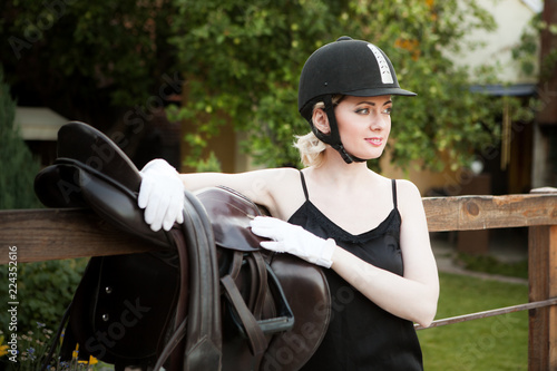 Young beautiful woman in jockey clothes with saddle for riding