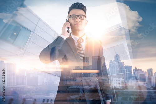 Photography The double exposure image of the businessman using a smartphone during sunrise overlay with cityscape image