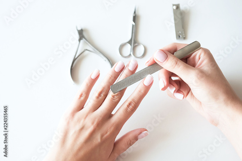 Woman making manicure with nail care tools background. French manicure.