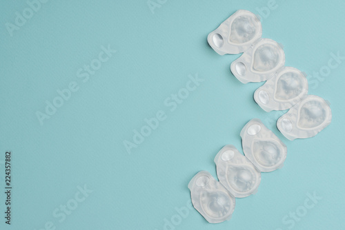 flat lay with contact lenses in white containers arranged on blue background