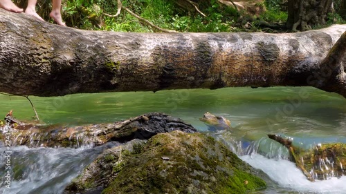 people are moving on a log over a river