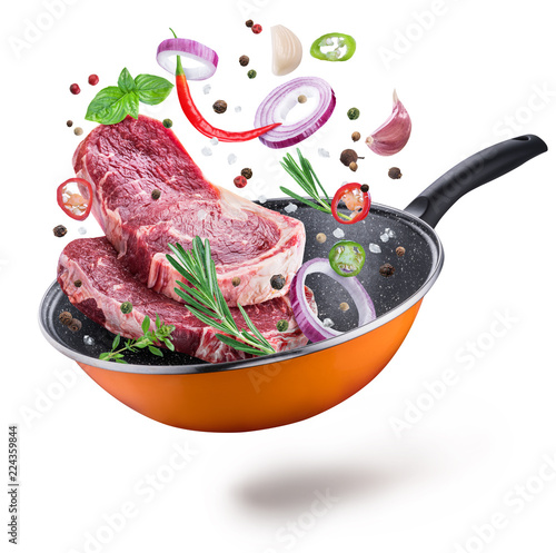 Flying meat steaks and spices over a frying pan. File contains clipping path.