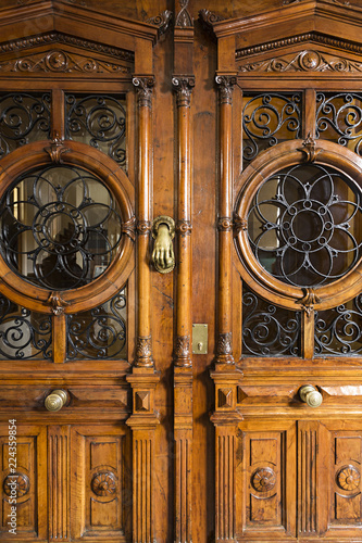 Puerta antigua de madera tallada con cristales y rejas.