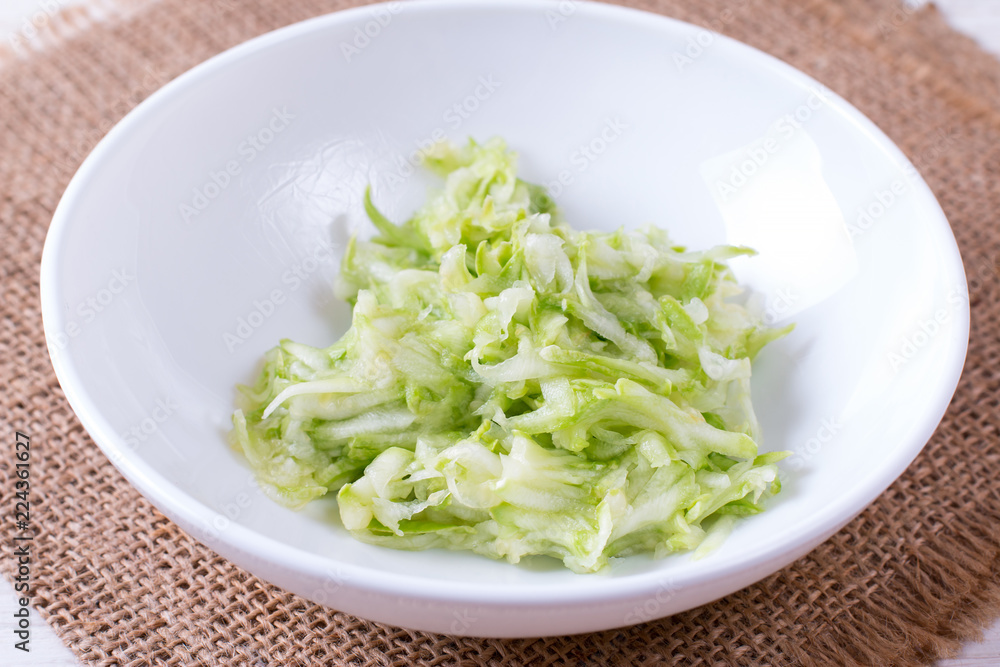 Bowl of grated zucchini on a white background Bowl of grated zucchini on a white background