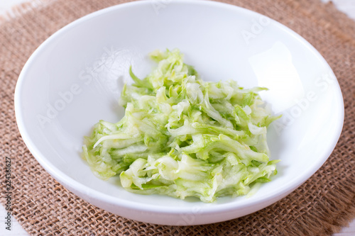 Bowl of grated zucchini on a white background