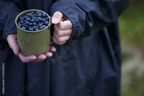 Full metal cup with fresh blueberries in hands