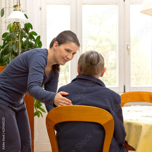 Fotografie Rear view of a senior woman sitting at home talking to a younger woman from a do