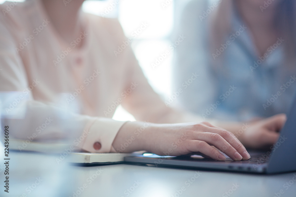 Close up shot businesswoman working on a laptop with her hands in the office with a modern design Close up shot businesswoman working on a laptop with her hands in the office with a modern design