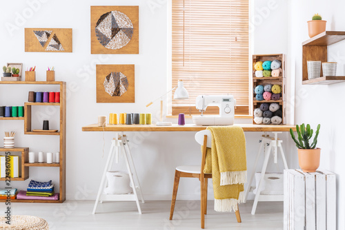 Real photo of a colorful room interior with a desk, sewing machine and threads photo