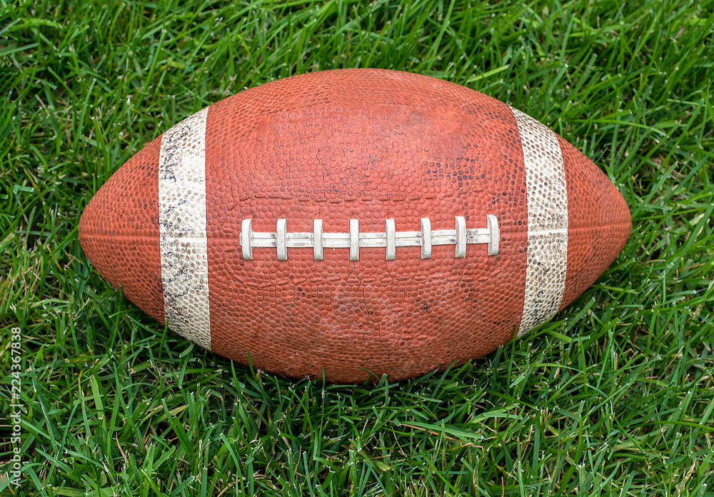 Obraz premium used football centered on green turf