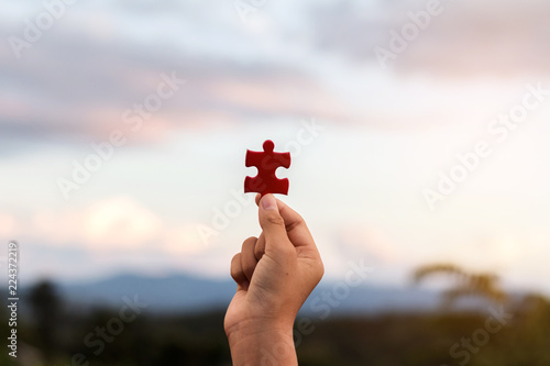 hands holding piece of red jigsaw puzzle