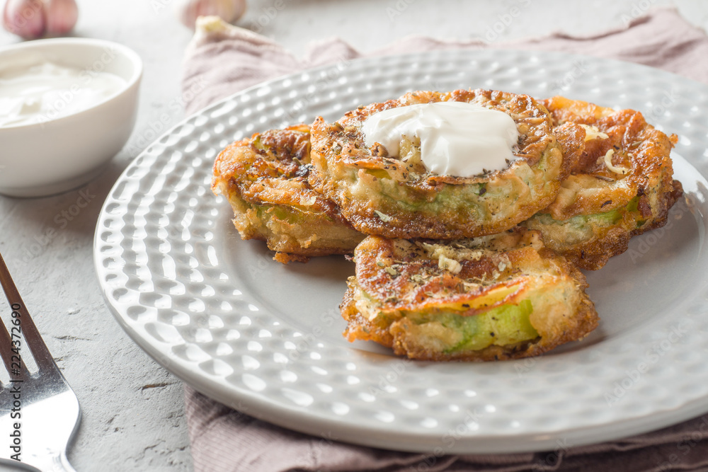 Fried zucchini slices in egg batter with garlic on a plate. Fried zucchini slices in egg batter with garlic on a plate.