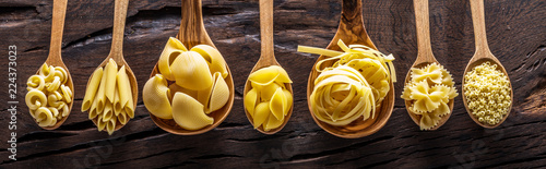 Photo Different pasta types in wooden spoons on the table. Top view.