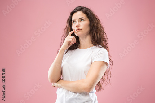 Remember all. Let me think. Doubt concept. Doubtful, thoughtful woman remembering something. Young emotional woman. Human emotions, facial expression concept. Studio. Isolated on trendy pink. Front
