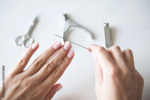 Woman making manicure with nail care tools background. French manicure.
