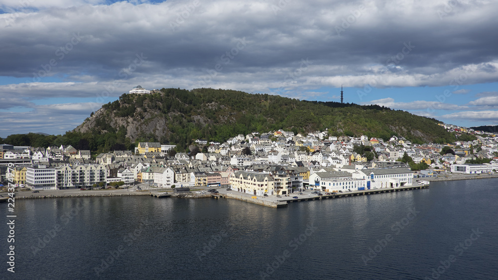 Horizontal shot with perspective from the fjord of Alesund, a tranquil port town with architecture in Art Nouveau style, and Mount Aksla in the background at the entrance to the Geirangerfjord, Norway