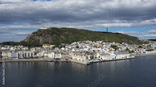 Horizontal shot with perspective from the fjord of Alesund, a tranquil port town with architecture in Art Nouveau style, and Mount Aksla in the background at the entrance to the Geirangerfjord, Norway