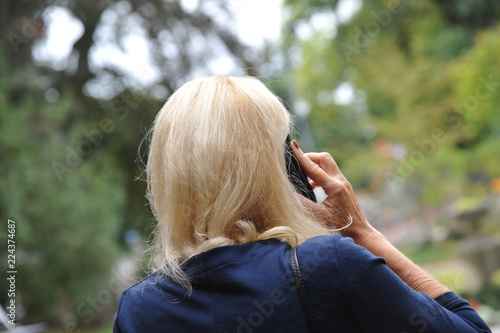 Fotografie blonde frau geschäftsfrau beim telefonieren mit handy am ohr  outdoor