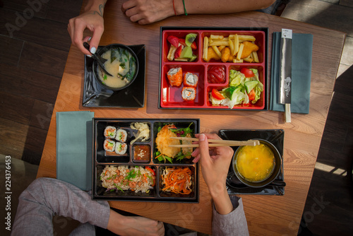Girls sit at a table in a Pan-Asian restaurant and eat lunch, bento box. Девушки сидят за столом в пан азиатском ресторане и едят ланч, бенто бокс.