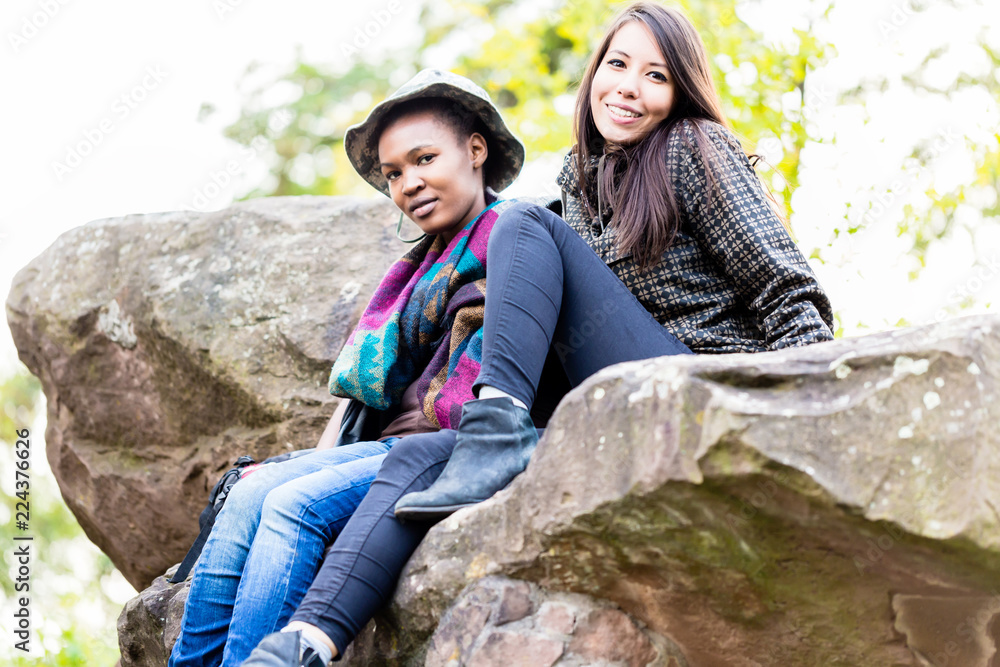 Naklejka premium Close-up of two young females friends sitting on rock