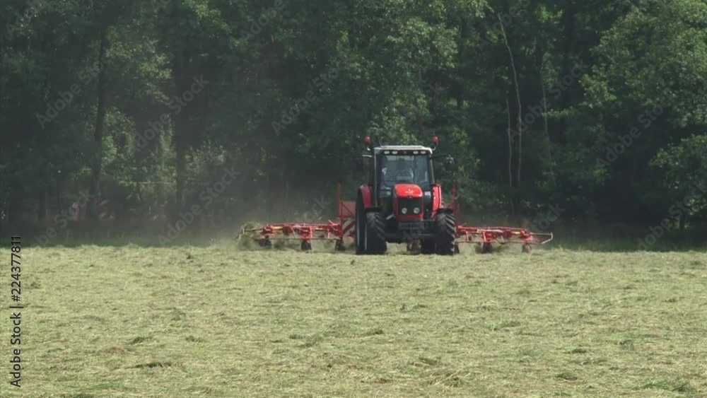Tractor in hayland, shakes out and loosens hay so as to dry it faster - on camera. Organic agriculture is a production system that sustains the health of soils, ecosystems and people. Tractor in hayland, shakes out and loosens hay so as to dry it faster - on camera. Organic agriculture is a production system that sustains the health of soils, ecosystems and people.