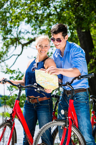 Portrait of couple holding map standing with two bicycle