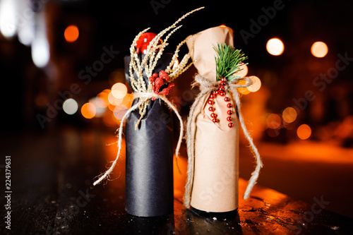 Two adorable christmas decorated bottles standing on the wooden bench