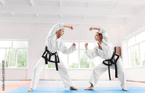 Two sporty woman fighting at karate training in martial arts school.