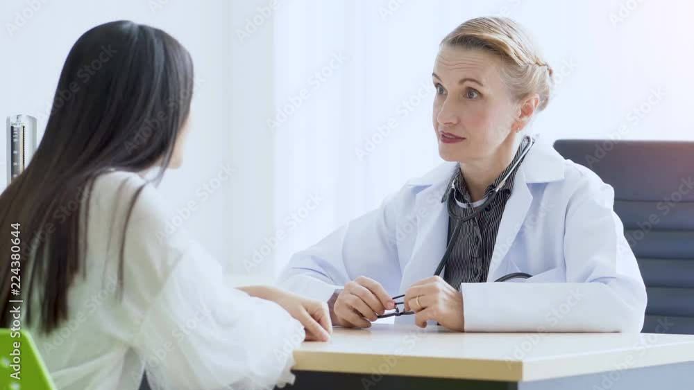 Senior female doctor talked and questioned the patient at the examination room. Senior female doctor talked and questioned the patient at the examination room.