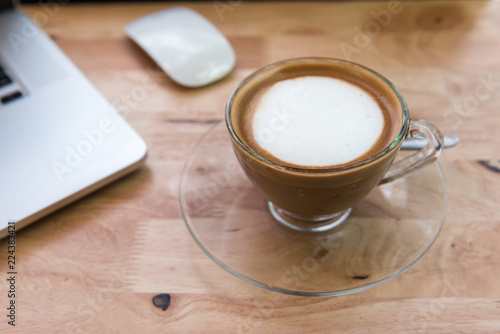 Cappuccino coffee cup with laptop computer and mouse on wooden table