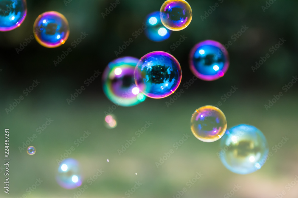 Group of colorful, mostly blue soap bubbles at the green background in a garden