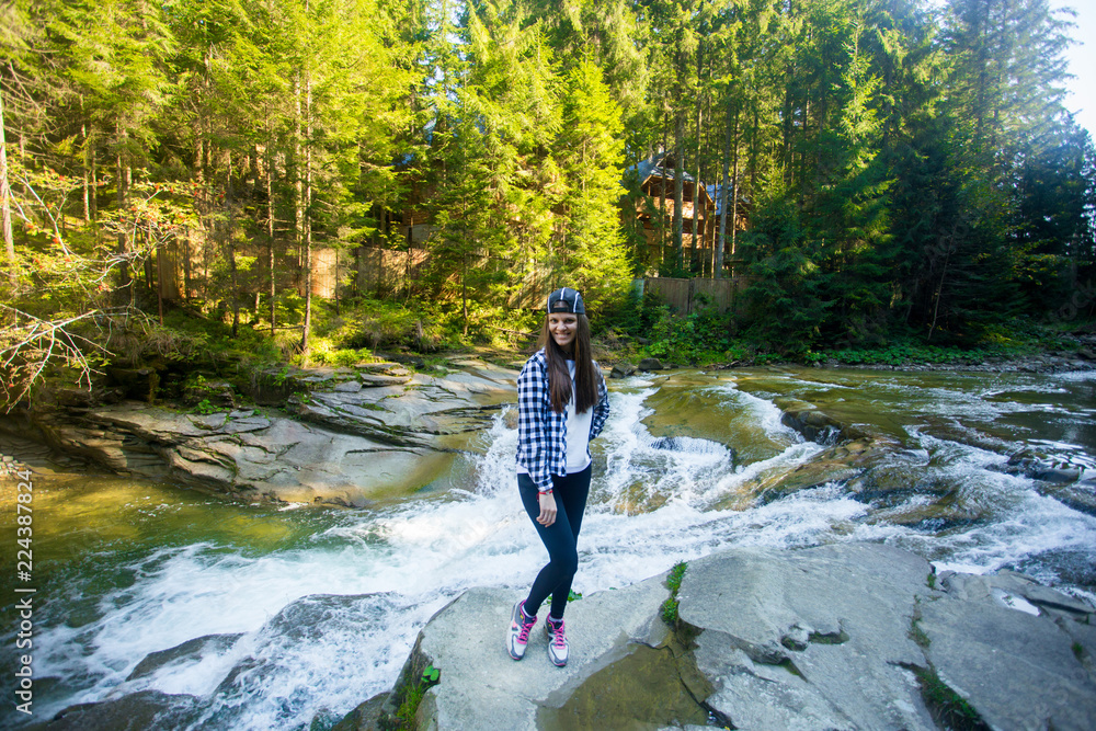 Young woman on edge of rock near fast river in middle of forest Young woman on edge of rock near fast river in middle of forest