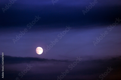 Full moon shining on the sky in cloudy day.