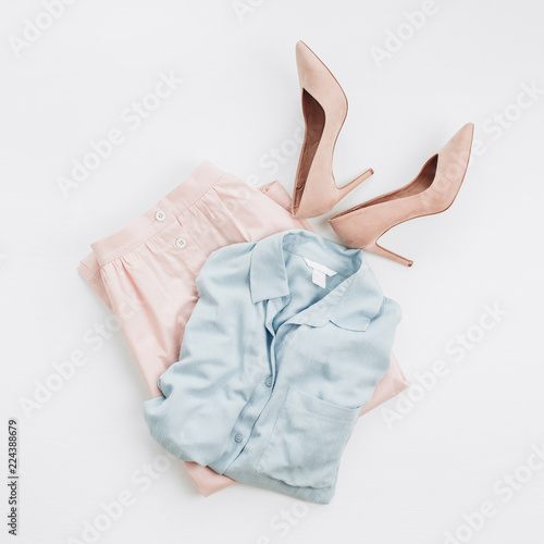 Woman pastel clothes: jeans shirt, skirt, high-heel shoes on white background. Flat lay, top view female fashion collage.