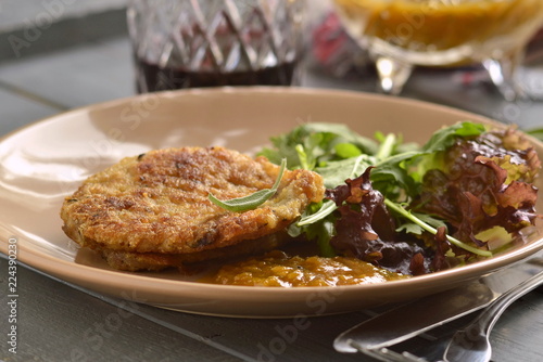 Fried pork chop with fresh herbs and fruit sauce, soft focus