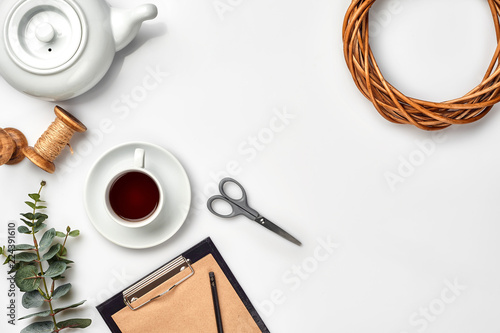 Still life with tea cup and the contents of a workspace composed. Different objects on white table. Flat lay