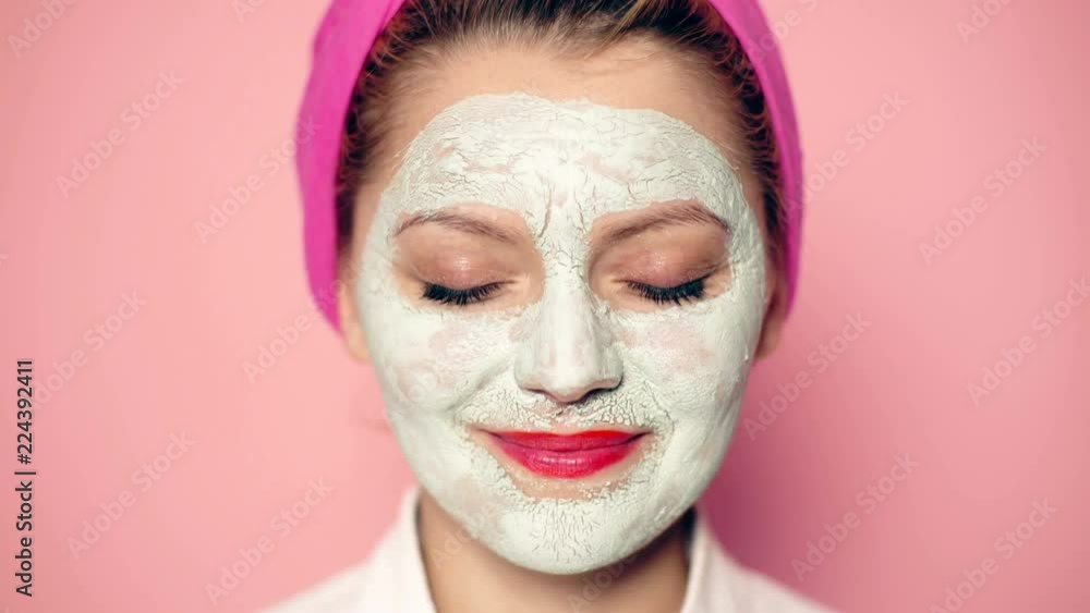 Close-up of a girl with a mask on her face and a towel on her head with a wide-open eyes smiling. Beautiful girl with cosmetic mask on her face. Woman wearing face mask. Face care concept. Close-up of a girl with a mask on her face and a towel on her head with a wide-open eyes smiling. Beautiful girl with cosmetic mask on her face. Woman wearing face mask. Face care concept.