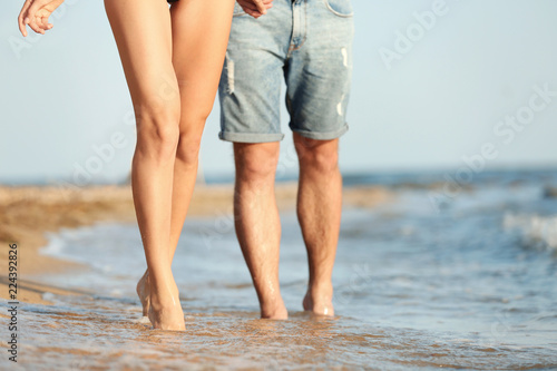 Young couple spending time together on beach, closeup of legs