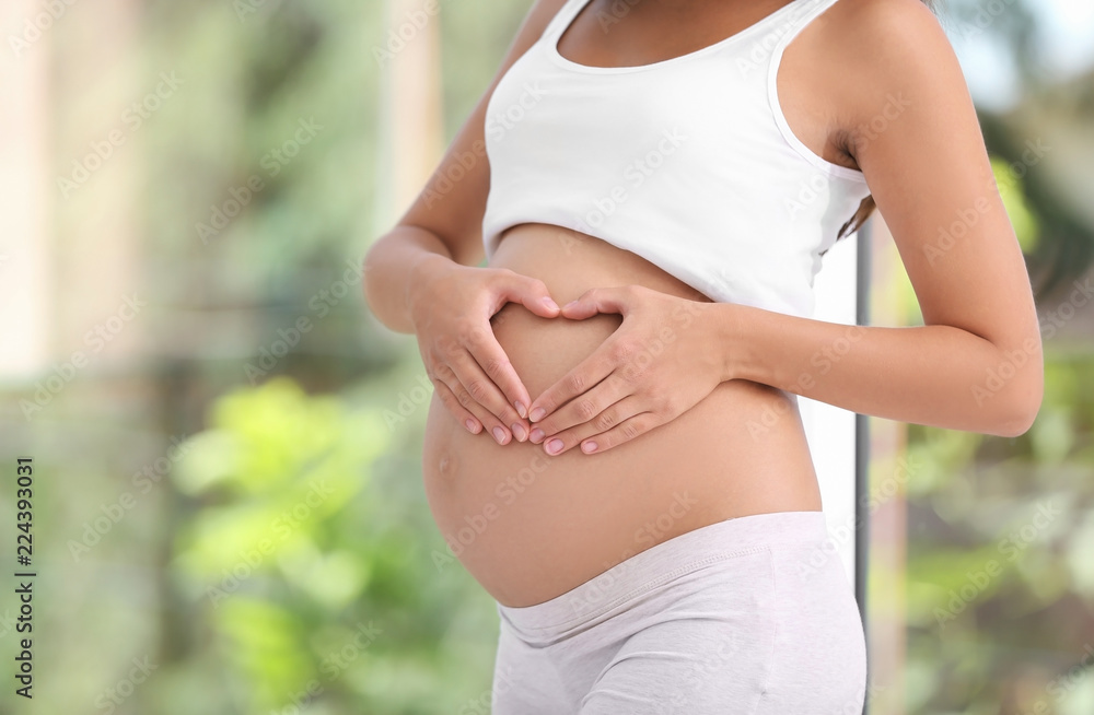 Pregnant woman standing near window at home, closeup Pregnant woman standing near window at home, closeup