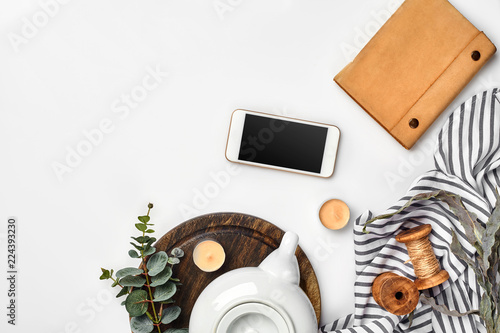 Still life with tea cup and the contents of a workspace composed. Different objects on white table. Flat lay