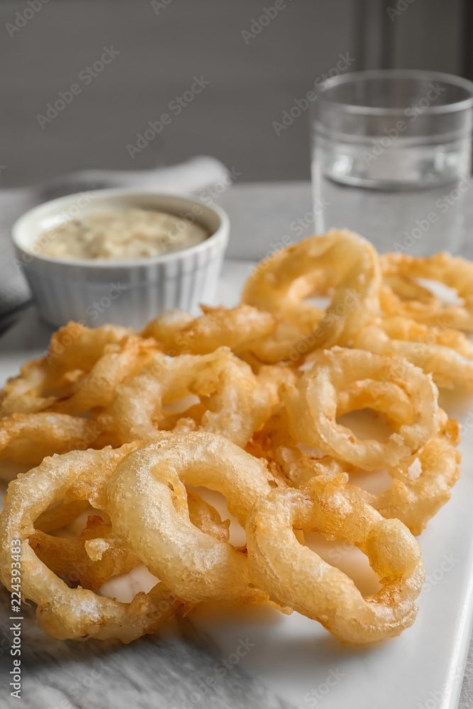 Closeup view of delicious golden breaded and deep fried crispy onion rings on marble board Closeup view of delicious golden breaded and deep fried crispy onion rings on marble board