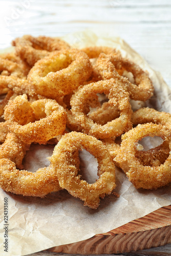 Homemade crunchy fried onion rings on wooden board, closeup