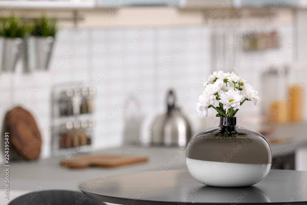 Vase with beautiful flowers on table in kitchen interior. Space for text Vase with beautiful flowers on table in kitchen interior. Space for text