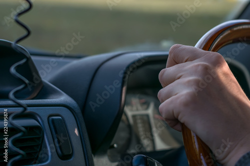 view of a people hand holding the wheel of a car, close-up