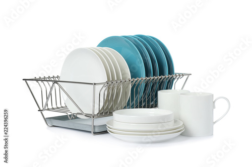 Rack with dishes and clean tableware on white background