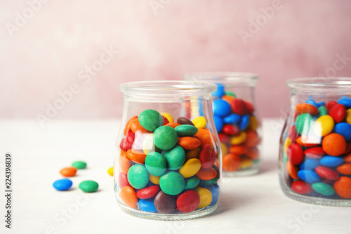 Jars with small colorful candies on table