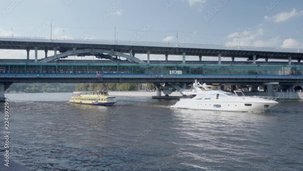 Ships sailing along river and glass bridge with passing train Ships sailing along river and glass bridge with passing train